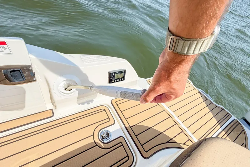 Slide: The Image of Man using a hose on a 2021 Sea Ray SDX 270 Outboard boat deck. - 25