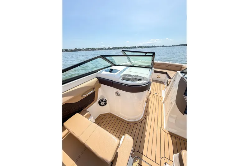 Slide: The Image of 2021 Sea Ray SDX 270 Outboard boat interior with tan seating and wood flooring on a sunny day. - 9