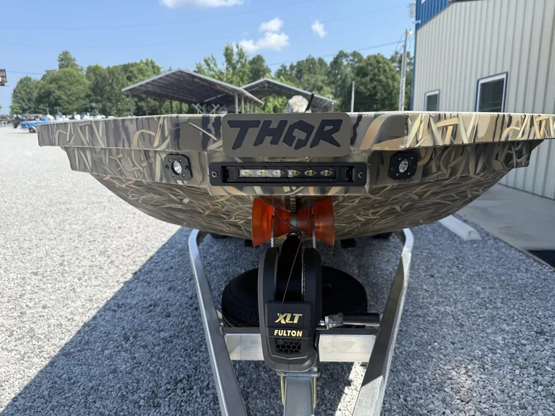Slide: The Image of Front view of a Thor boat on a trailer, featuring camouflage pattern and an XLT Fulton winch mechanism. - 2