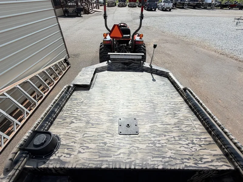 Slide: The Image of The boat has a camouflaged deck and is parked on a trailer next to a tractor. - 8
