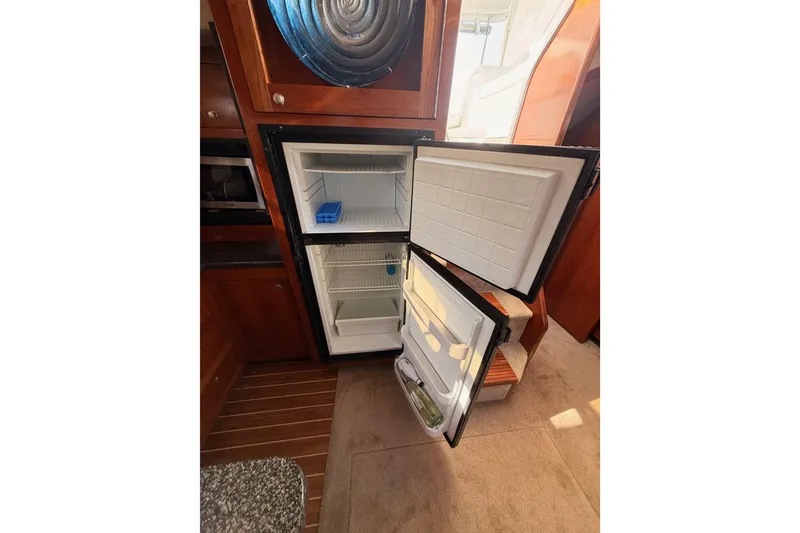 Slide: The Image of Open refrigerator inside 2005 Cruisers Yachts 405 Express Motoryacht, showcasing interior storage. - 44
