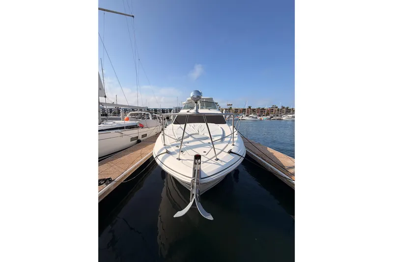 Slide: The Image of 2005 Cruisers Yachts 405 Express Motoryacht docked at marina under clear blue sky. - 2
