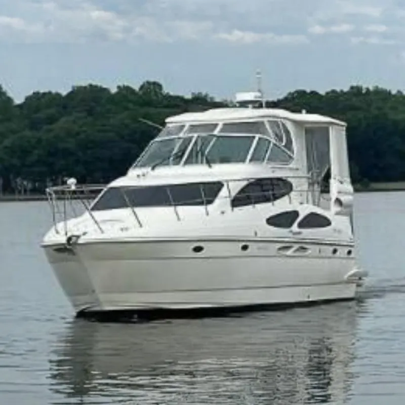 The Image of 2005 Cruisers Yachts 405 Express Motoryacht on calm water with a wooded shoreline. - 0