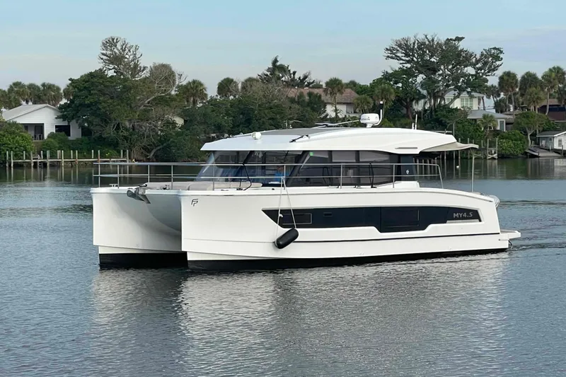 Slide: The Image of 2022 Fountaine Pajot MY4.S catamaran on calm water, surrounded by lush greenery. - 1