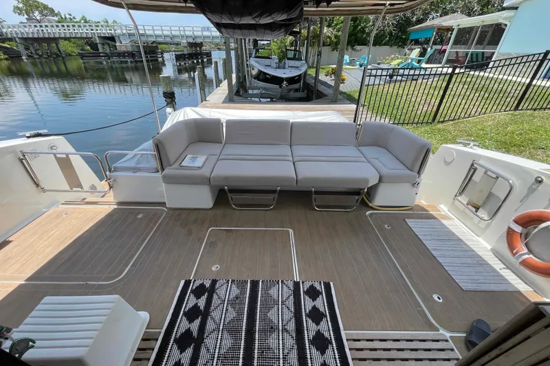 Slide: The Image of 2022 Fountaine Pajot MY4.S yacht deck with seating, docked by a serene waterfront. - 5