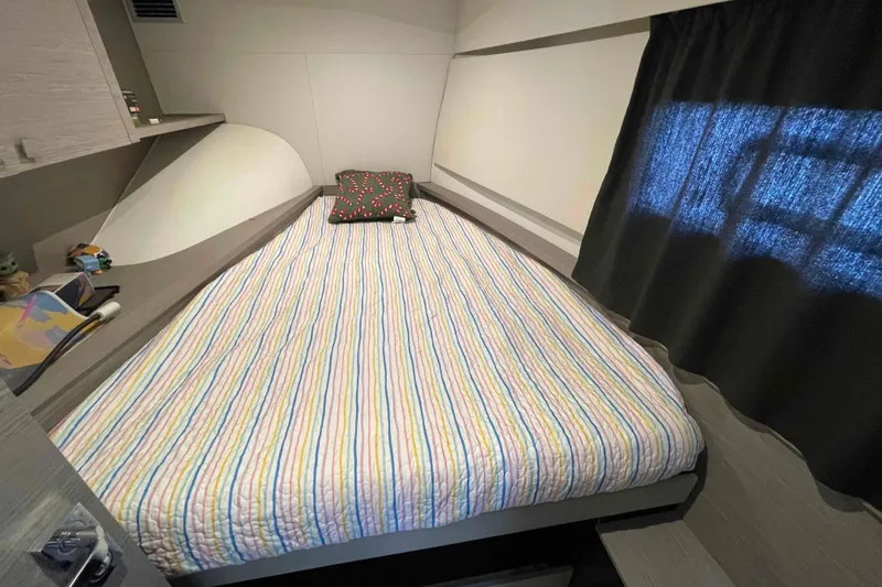 Slide: The Image of Cozy cabin interior of 2022 Fountaine Pajot MY4.S with striped bedding and decorative pillow. - 37