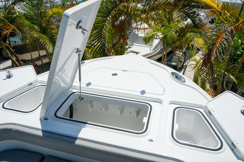 Slide: The Image of 2026 Blackfin 262 HB boat with open storage compartment, surrounded by tropical plants. - 27