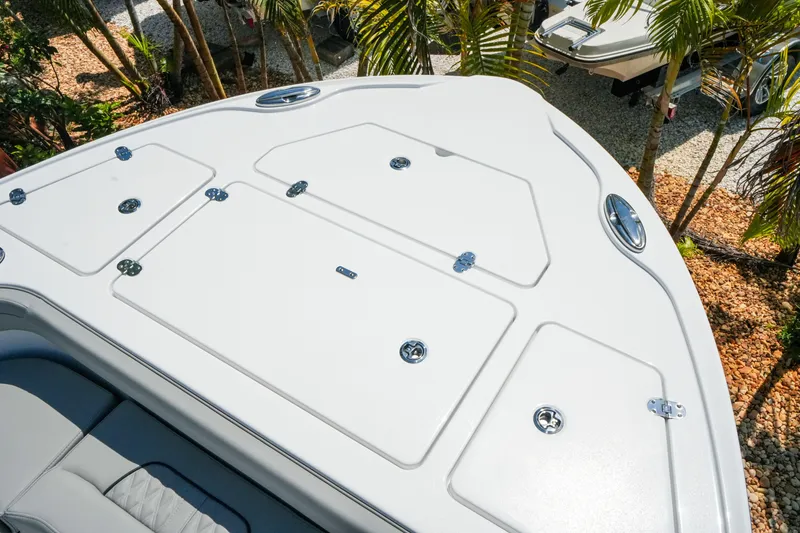 Slide: The Image of 2026 Blackfin 262 HB boat deck with storage compartments, surrounded by tropical foliage. - 19