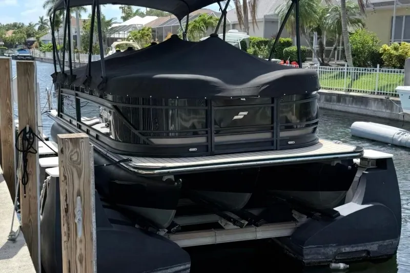 Slide: The Image of 2021 Starcraft SLS 3 pontoon boat docked in a canal, covered with a black tarp. - 4