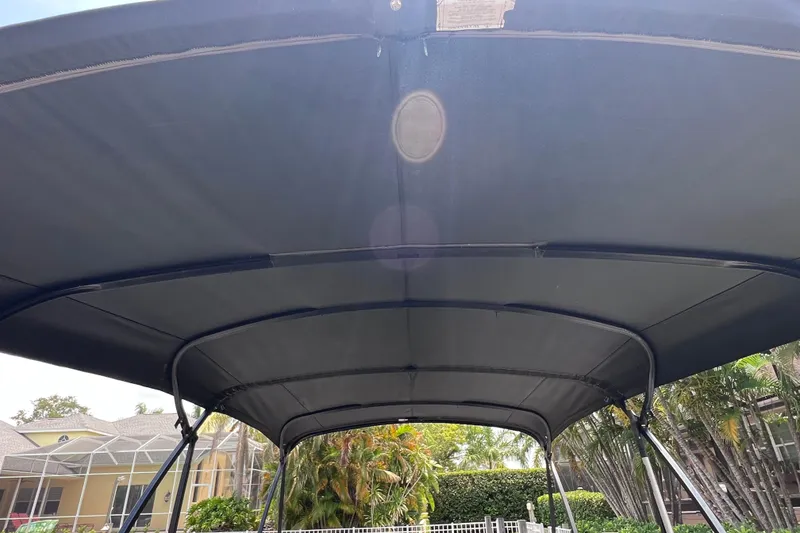 Slide: The Image of 2021 Starcraft SLS 3 boat canopy, black fabric, outdoor setting with trees and house. - 49