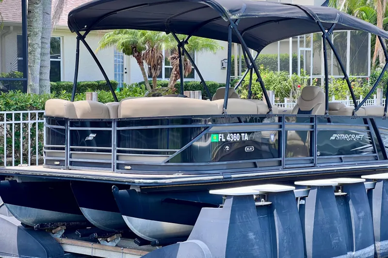 Slide: The Image of 2021 Starcraft SLS 3 pontoon boat with canopy, docked near a residential area. - 1