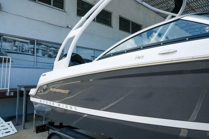 Slide: The Image of 2027 Four Winns HD2 OB boat, sleek design, parked near a building. - 3