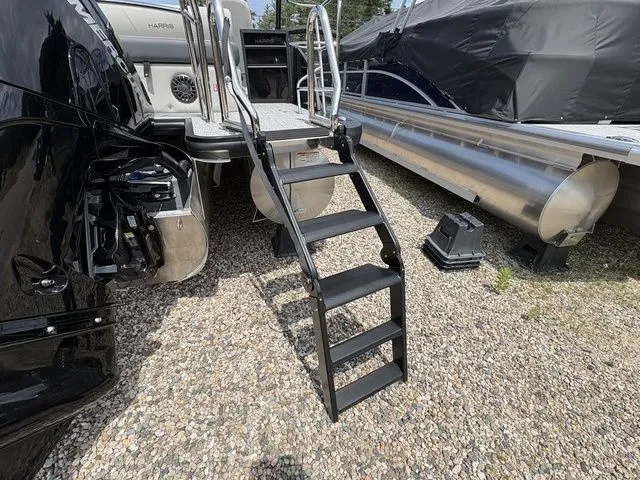 Slide: The Image of A 2026 Harris Cruiser 230 with a sturdy ladder at the stern, on a gravel surface. - 3