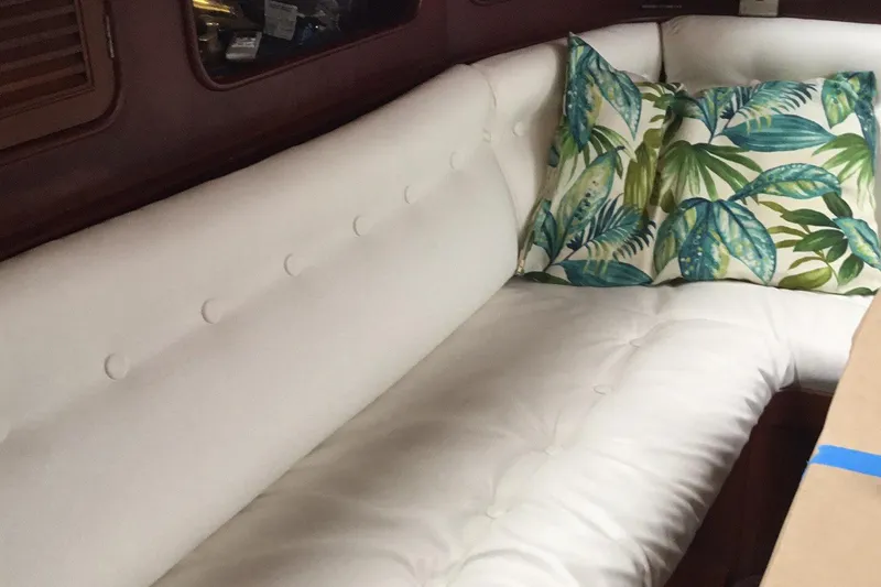 Slide: The Image of Interior of 1987 Tayana 52 yacht with white cushioned seating and tropical pillows. - 28