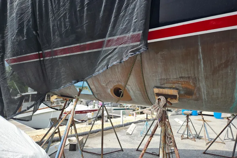 Slide: The Image of 1987 Tayana 52 sailboat on stands, partially covered, undergoing maintenance. - 34