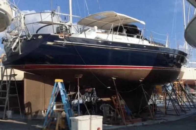 The Image of 1987 Tayana 52 sailboat on dry dock, blue hull, red stripe, under maintenance. - 0