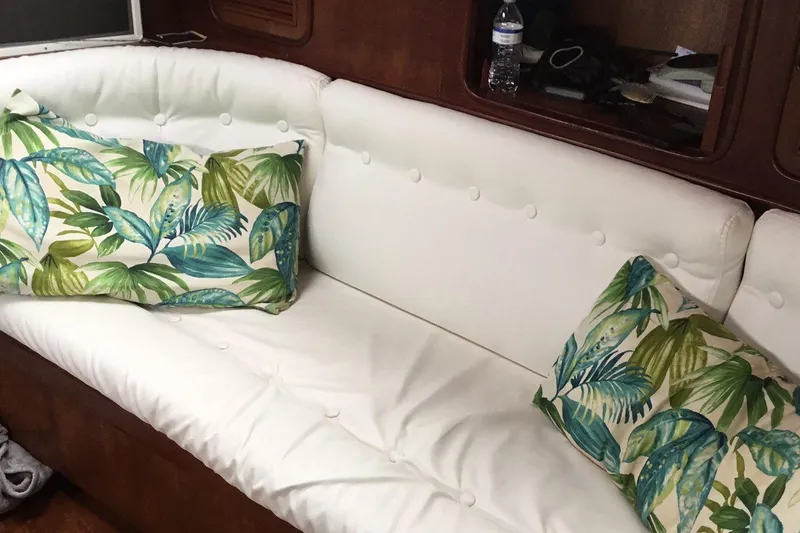 Slide: The Image of White cushioned seating with tropical leaf pillows on a 1987 Tayana 52 yacht. - 26