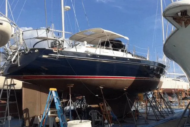 The Image of 1987 Tayana 52 sailboat on dry dock, blue hull, red stripe, under maintenance. - 0