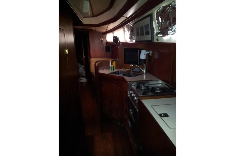 Slide: The Image of Interior of 1987 Tayana 52 yacht featuring a compact kitchen with wooden cabinetry. - 14