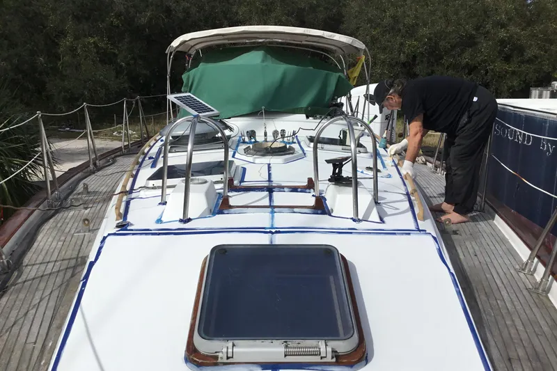 Slide: The Image of Person working on deck of 1987 Tayana 52 sailboat, featuring solar panel and hatch. - 4