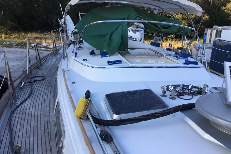 Slide: The Image of 1987 Tayana 52 sailboat deck with green cover and equipment, docked outdoors. - 7
