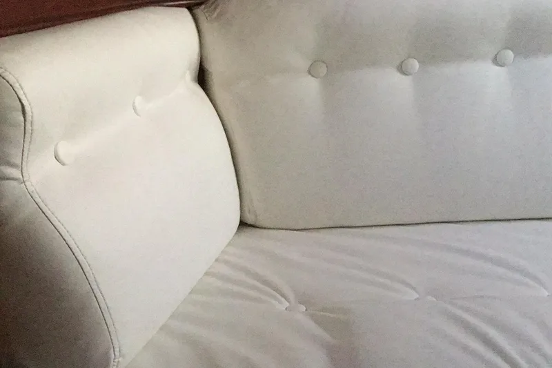 Slide: The Image of White cushioned seating on a 1987 Tayana 52 yacht, featuring button-tufted design. - 25