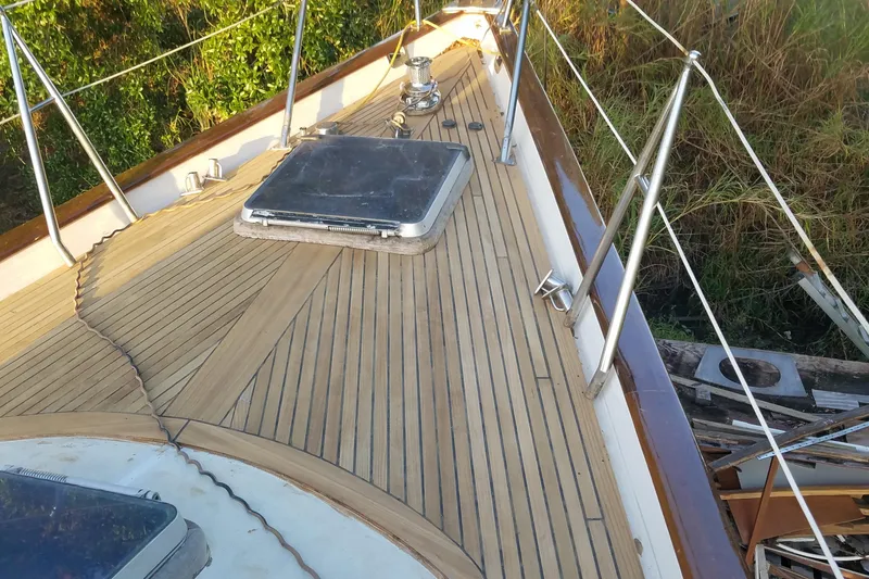 Slide: The Image of Deck of 1987 Tayana 52 sailboat with teak wood finish and metal railings. - 2
