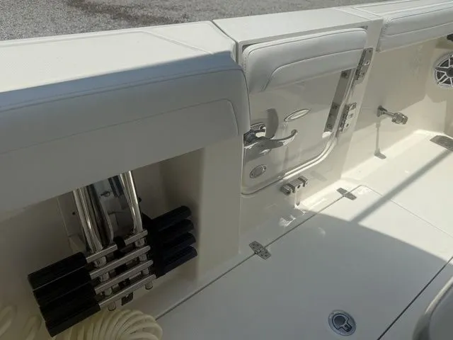 Slide: The Image of The image shows the deck of a 2025 Cobia 265 Open Center Console boat with storage and rod holders. - 27