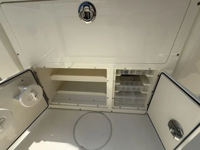Slide: The Image of The image shows the storage area of a Cobia 265 Open Center Console boat. There are open shelves and drawers. - 21