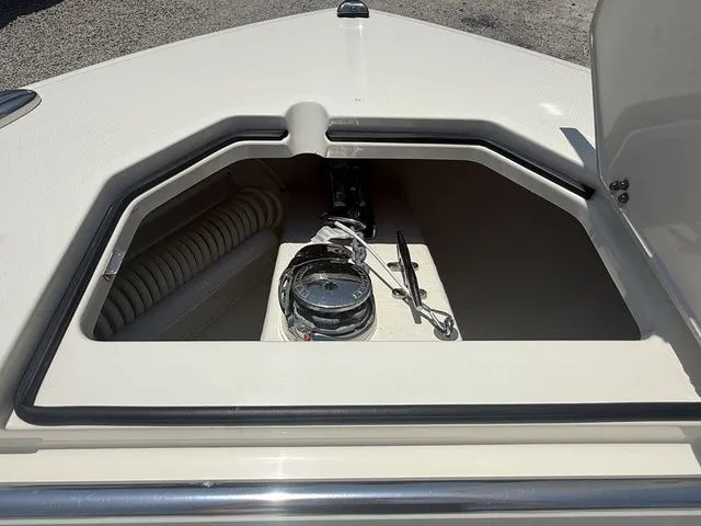 Slide: The Image of The bow of a Cobia 265 Open Center Console boat features a storage compartment with rope and tools. - 10