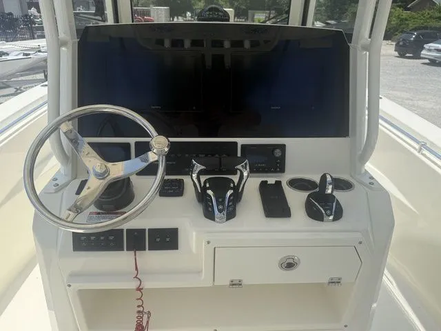 Slide: The Image of The image shows the helm of a Cobia 265 Open Center Console boat. It features a modern design with a large steering wheel and multiple instruments. - 18