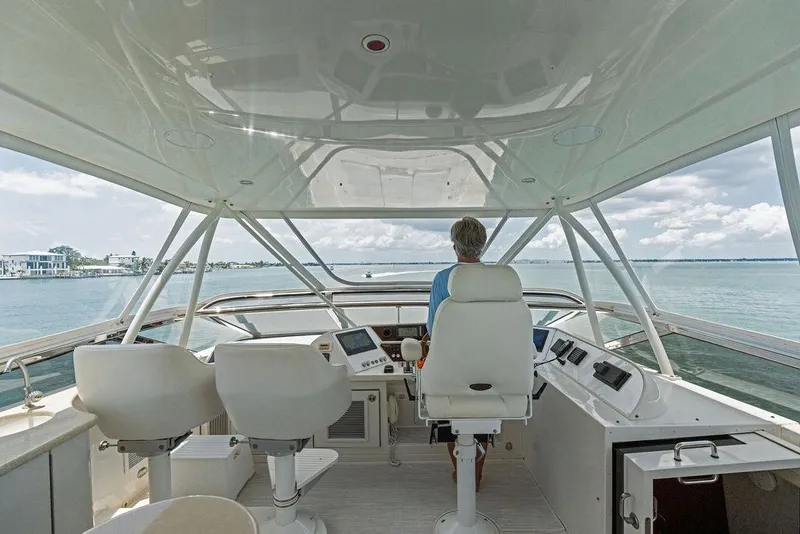 Slide: The Image of Person steering 2005 Marquis 65 MY yacht on open water, under clear skies. - 57