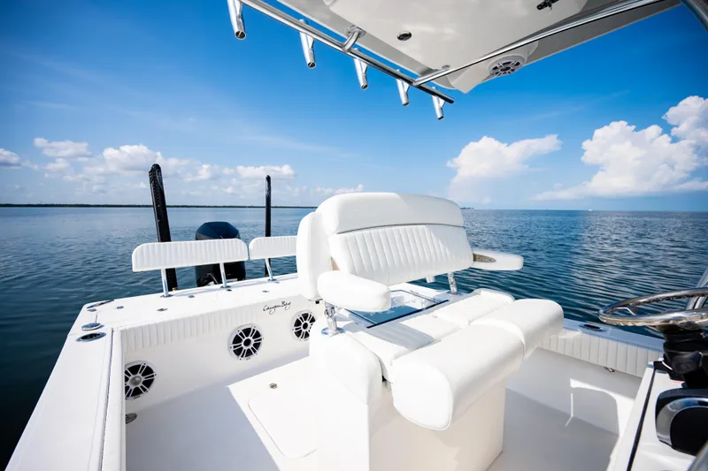 Slide: The Image of 2023 Canyon Bay 28h boat interior with white seating, ocean view, and clear blue sky. - 34