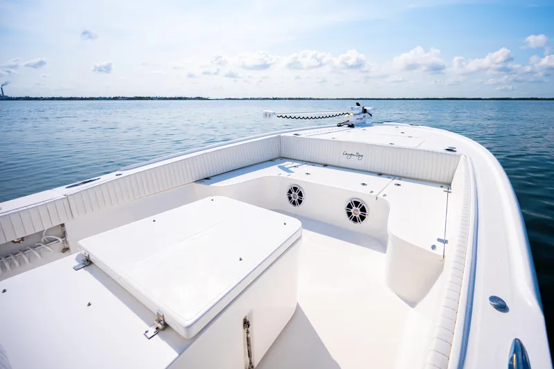 Slide: The Image of 2023 Canyon Bay 28h boat on calm water, showcasing spacious deck and seating. - 15