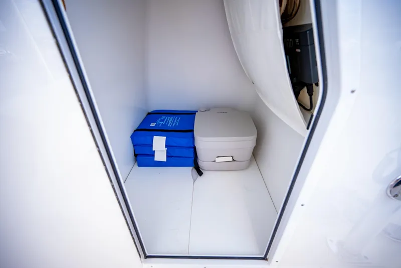 Slide: The Image of Storage compartment in 2023 Canyon Bay 28h boat with blue life jackets and portable toilet. - 41