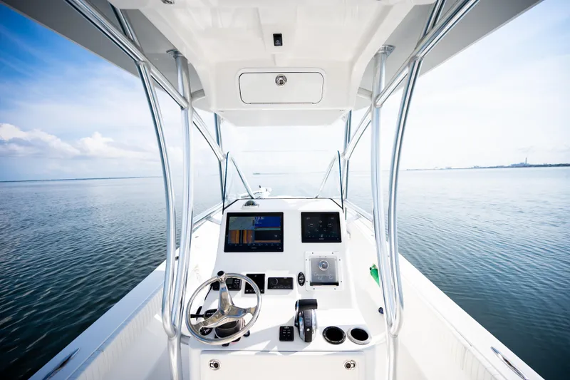 Slide: The Image of 2023 Canyon Bay 28h boat dashboard with steering wheel and navigation screens on open water. - 33
