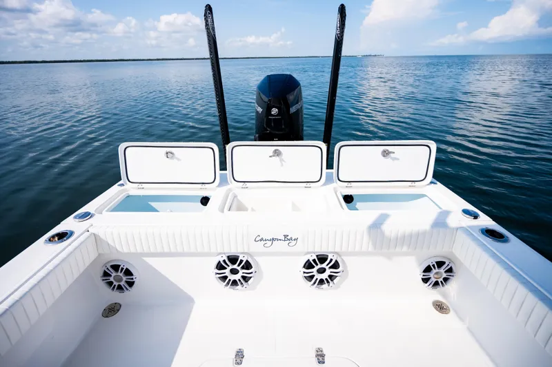 Slide: The Image of 2023 Canyon Bay 28h boat with open storage compartments on calm water. - 52