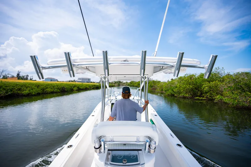 Slide: The Image of 2023 Canyon Bay 28h boat navigating a scenic waterway under a clear blue sky. - 53