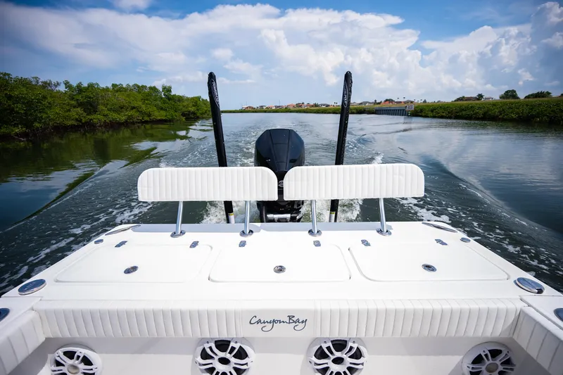 Slide: The Image of 2023 Canyon Bay 28h boat cruising on a scenic waterway under a blue sky. - 43