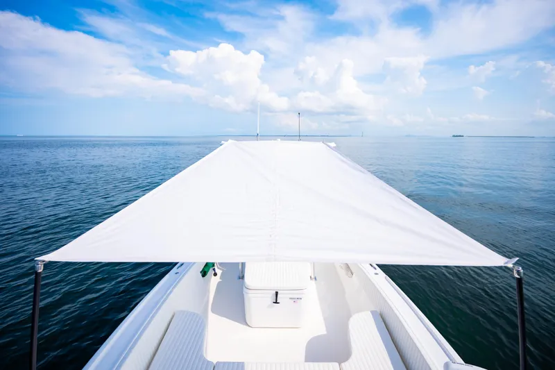 Slide: The Image of 2023 Canyon Bay 28h boat with canopy on calm ocean waters under blue sky. - 23