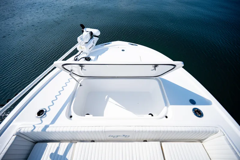 Slide: The Image of 2023 Canyon Bay 28h boat deck with open storage compartment on calm water. - 16