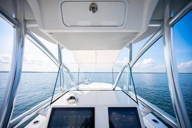 Slide: The Image of Canyon Bay 28h boat dashboard view, 2023 model, on calm ocean waters. - 31