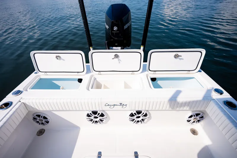 Slide: The Image of Canyon Bay 28h boat deck with storage compartments, 2023 model, on calm water. - 39