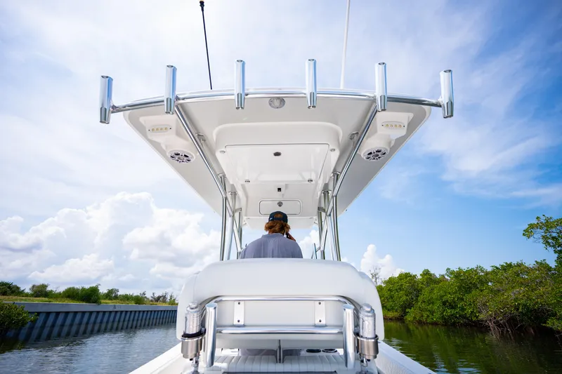 Slide: The Image of 2023 Canyon Bay 28h boat navigating a scenic waterway under a clear blue sky. - 38