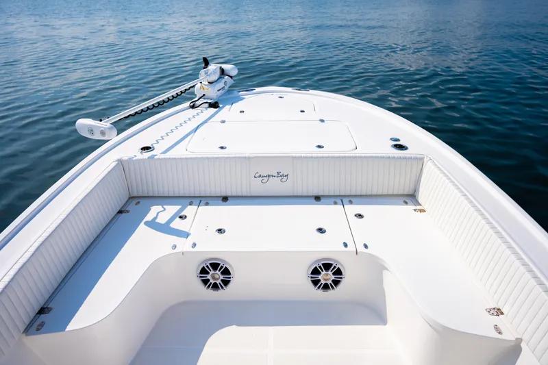 Slide: The Image of 2023 Canyon Bay 28h boat deck with storage compartments and trolling motor on calm water. - 10