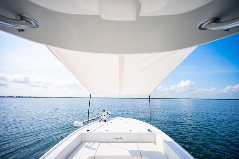 Slide: The Image of 2023 Canyon Bay 28h boat with canopy, cruising on calm blue waters under a clear sky. - 24
