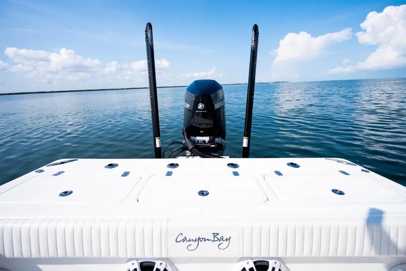 Slide: The Image of 2023 Canyon Bay 28h boat on calm water, featuring a powerful Mercury engine. - 46