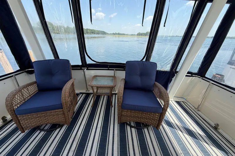 Slide: The Image of 1996 Carver 400 Cockpit Motor Yacht interior with wicker chairs and striped rug, overlooking water. - 15