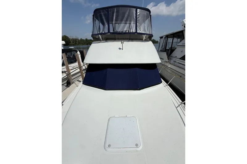 Slide: The Image of 1996 Carver 400 Cockpit Motor Yacht with blue canopy, docked under clear skies. - 5