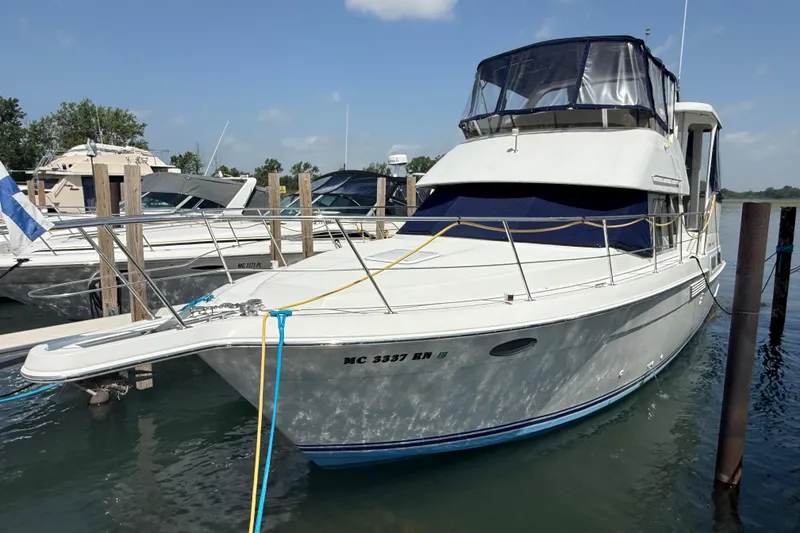 The Image of 1996 Carver 400 Cockpit Motor Yacht docked at marina under clear skies. - 0